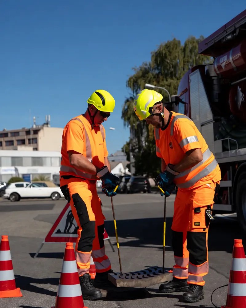 Deux techniciens Amoudruz SA ouvrant un regard de canalisation